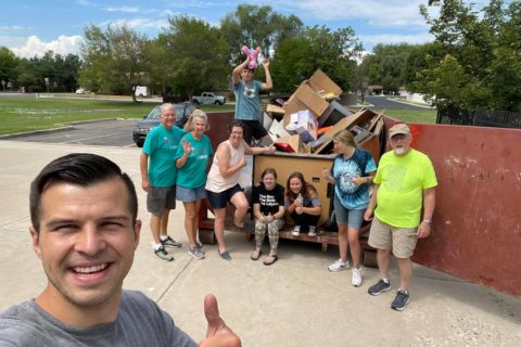 group cleaning and throwing things into a dumpster