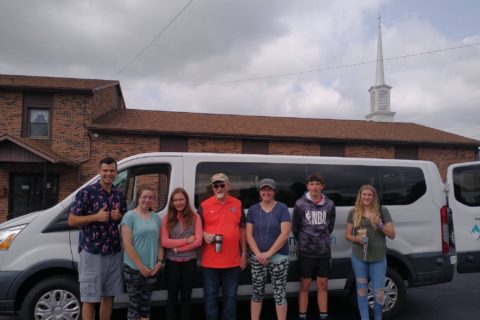 group of kids in front a church van