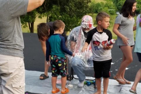 kids soak an adult with water balloons and shaving cream