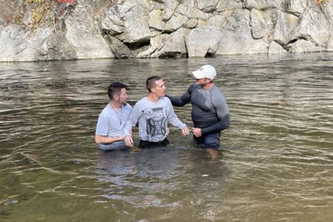 Three men in a river for a baptism
