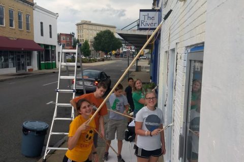 Teenagers help clean the front of a store