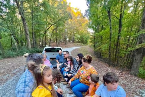 children and adults sitting across from each other on a trailer. Going for a hayride