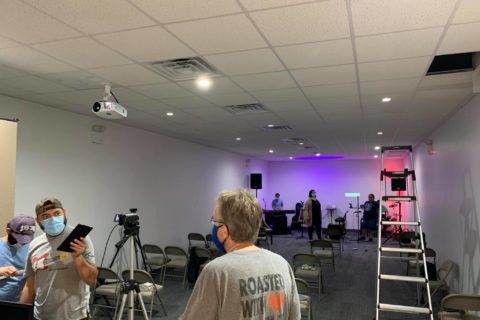 people set up tech for a worship service in a small room