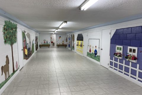 Large bright hallway decorated with wall paintings of the town of Bluff City