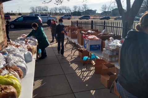 Newton Christian Church - packaged food is spread out on tables outside and people help bag and sort them