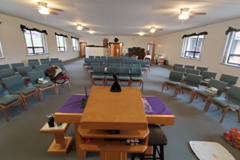 A church sanctuary is set up with chairs in a round with the pulpit front in center in front of the altar