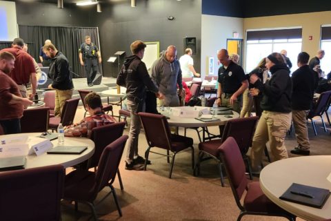 People gather around circle tables in a youth room